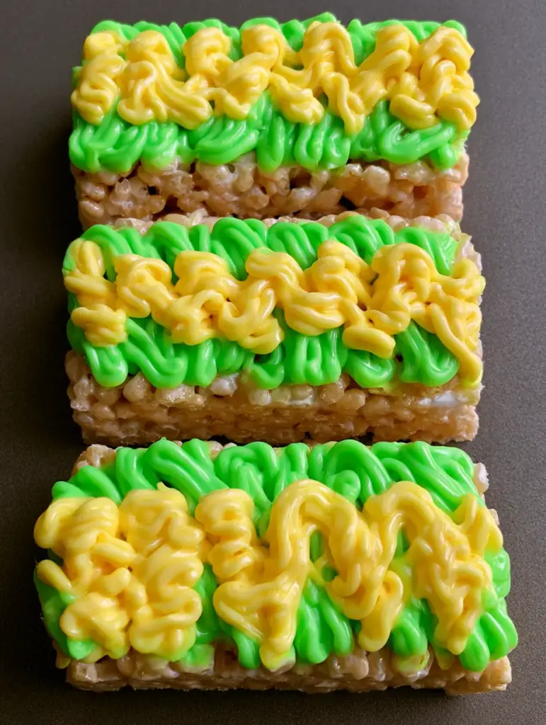 Close up view of rectangular puffed rice treats topped with neon green frosting drizzle. (Glow in the Dark Rice Krispie Treats)