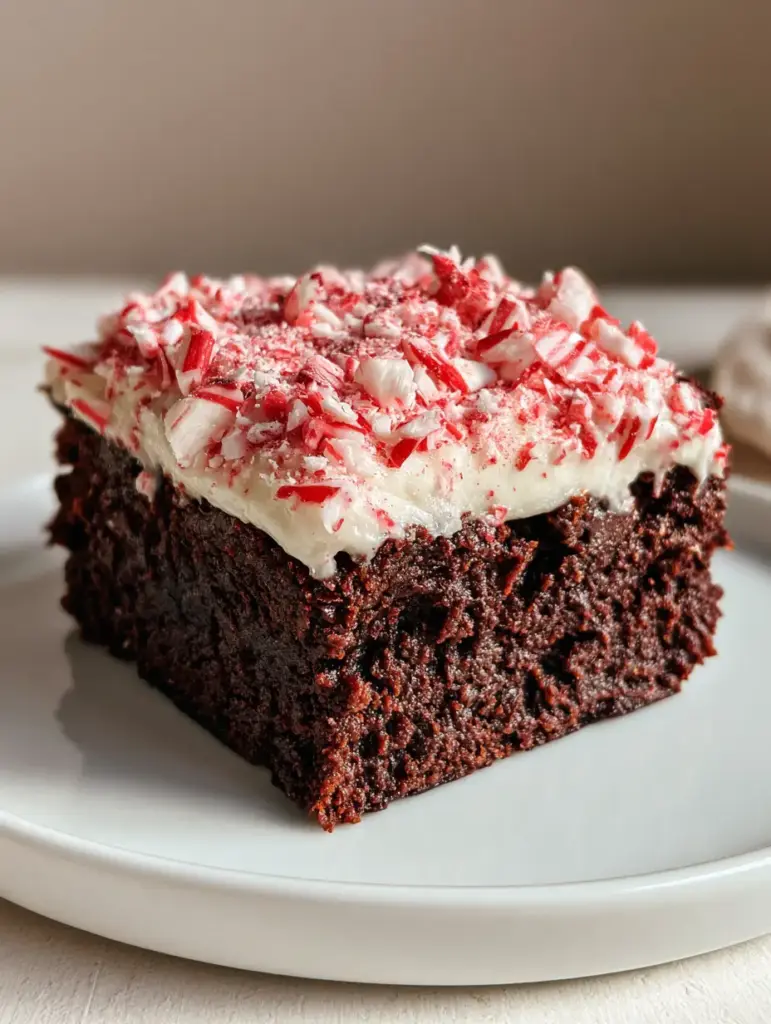 A close-up shot of a thick square slice of fudgy dark chocolate Peppermint Brownies with a half-inch layer of white frosting.